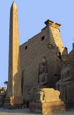 The obelisk and first pylon fronted by seated statues of Ramses II.